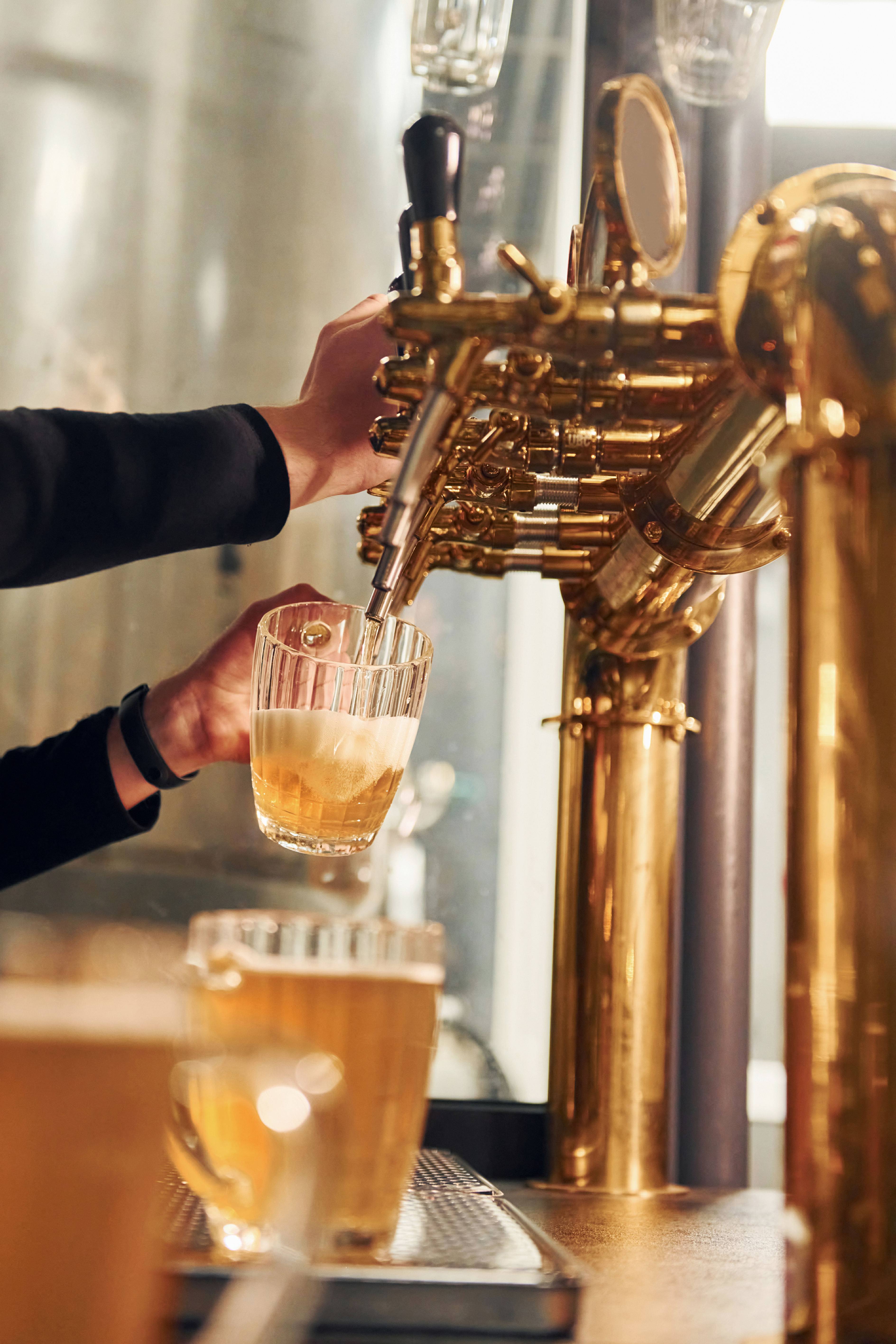 Side view of man's hands that fills glasses by beer